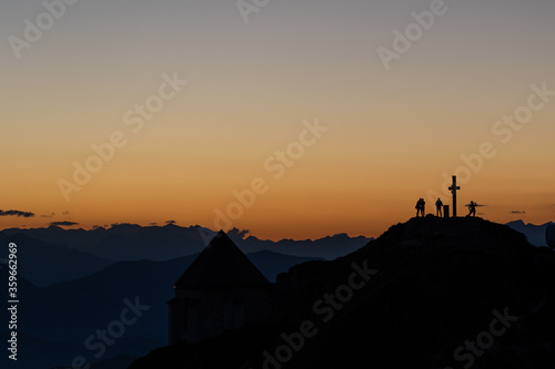 silhouette of hikers on a peak of a mountain top