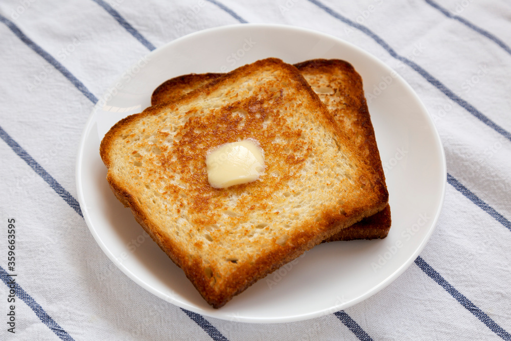 Homemade Buttered Toast on a white plate, side view.