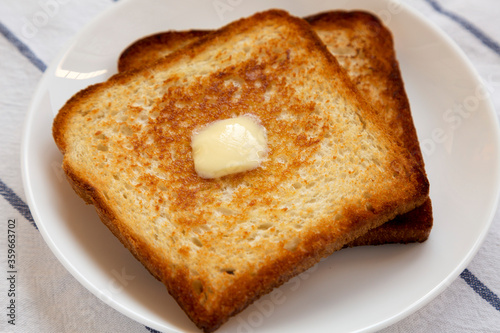 Homemade Buttered Toast on a white plate, low angle view. Close-up.