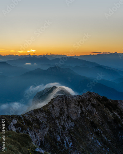 layers of mountains during sunset with a fog cloud