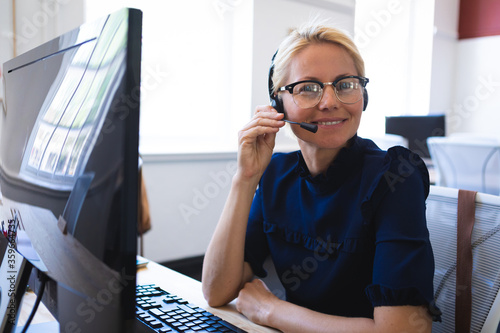 Mixed race woman talking on an earpiece while smiliing and looking at camera photo