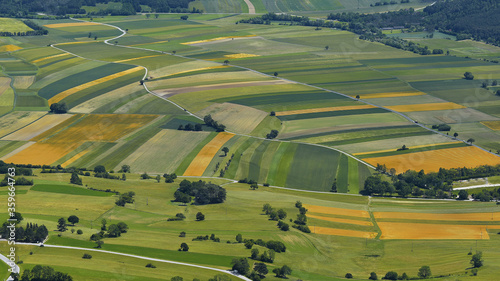sommerliche Landschaft mit nachhaltiger Landwirtschaft, Ernte von kleinräumigen Feldern mit reifem Getreide, buntes Muster von Feldern, vielfältige Felderanordnung, Escape als Flucht aufs Land
