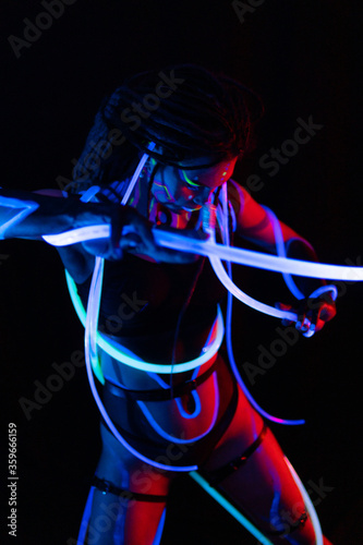 Portrait of a Warror Girl with Glowing Tubes in Neon UF Light. Model Girl with Dreadlocks and Fluorescent Creative Psychedelic MakeUp, Art Design of Female Disco Dancer Model in UV, Colorful Abstract photo