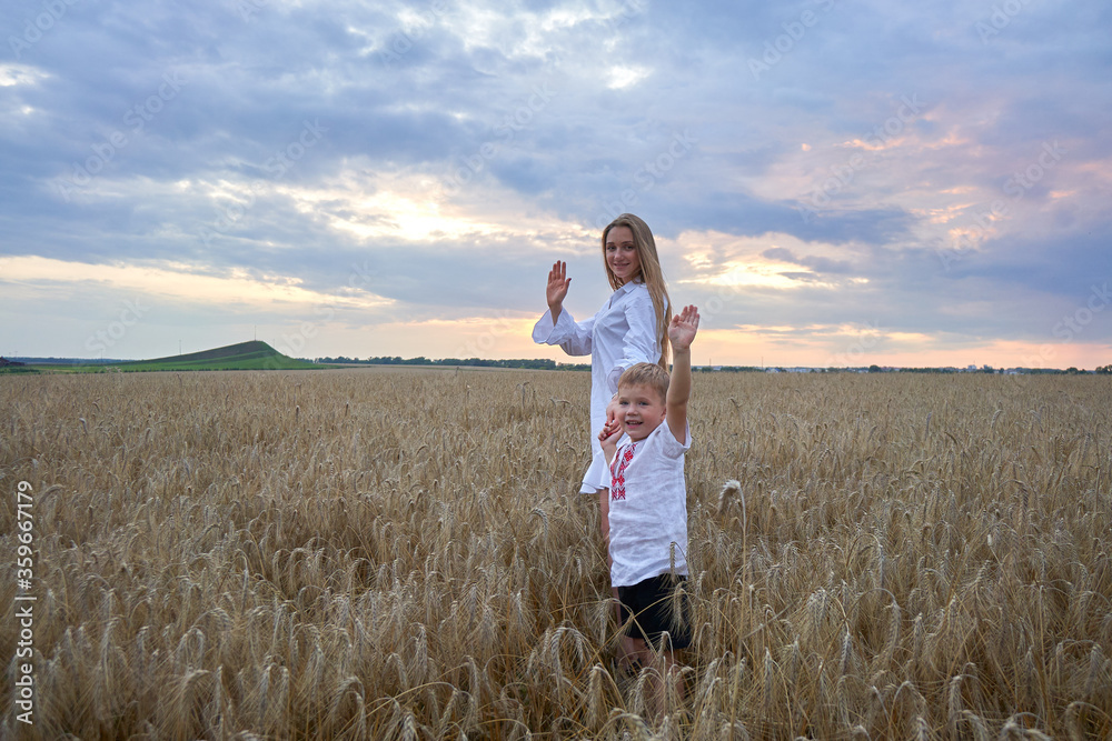 Happy mother and son are running through a wheat field