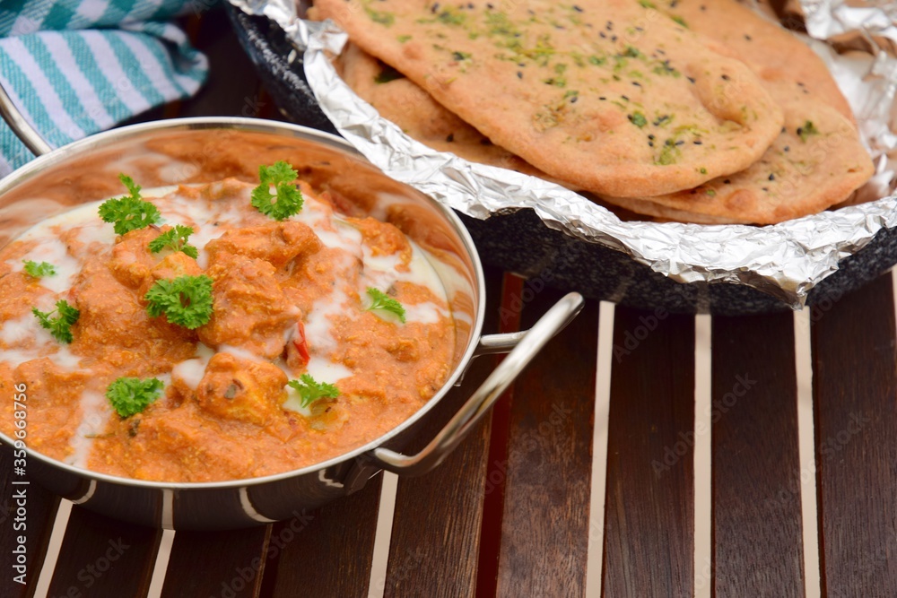 Murgh Makhani or butter chicken served with homemade whole wheat garlic