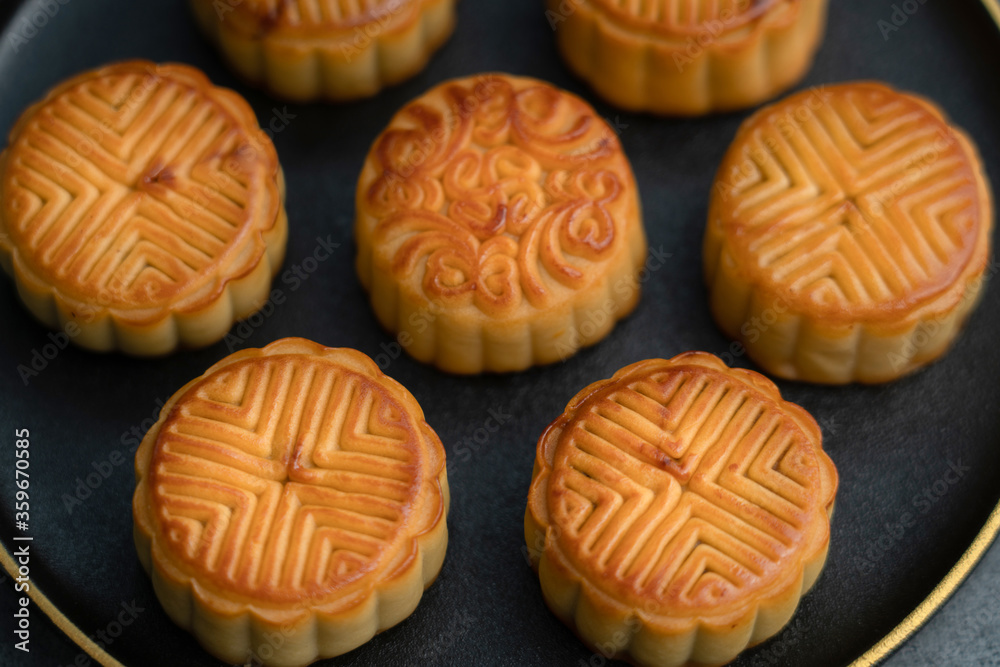 Mooncakes for the Mid-Autumn Festival are placed on a black plate with gold ornaments