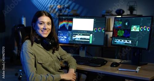 Foto Picture of professional female video editor editing video on his personal computer with two displays in modern video studio
