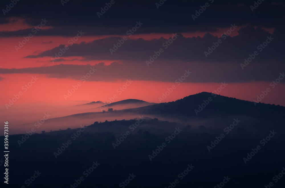 dark landscape, hills and mountains in mist at twilight