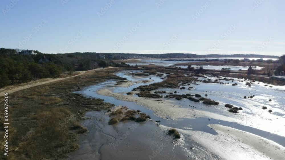 The camera swoops down and tilts to reveal beautiful highlights on the water during low tide at Duck Creek. You can see a flock of ducks in the stream. The camera swoops down and tilts to reveal beautiful highlights on the water during low tide at Duck Creek. You can see a flock of ducks in the stream.