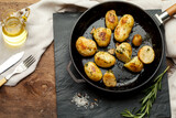 Chips in an iron pan. Rosemary, oil, young potatoes