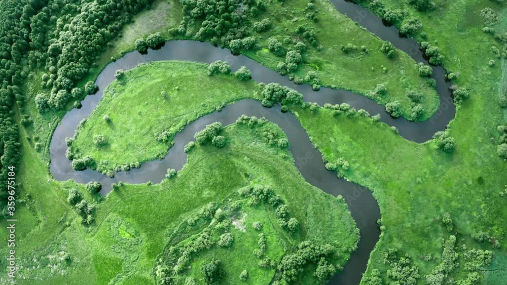 Drone flies over beautiful winding river flows through green meadows and forest. Aerial idyllic european landscape. Summer day. Birds eye view of flat wetland terrain in national park of Belarus Drone flies over beautiful winding river flows through green meadows and forest. Aerial idyllic european landscape. Summer day. Birds eye view of flat wetland terrain in national park of Belarus