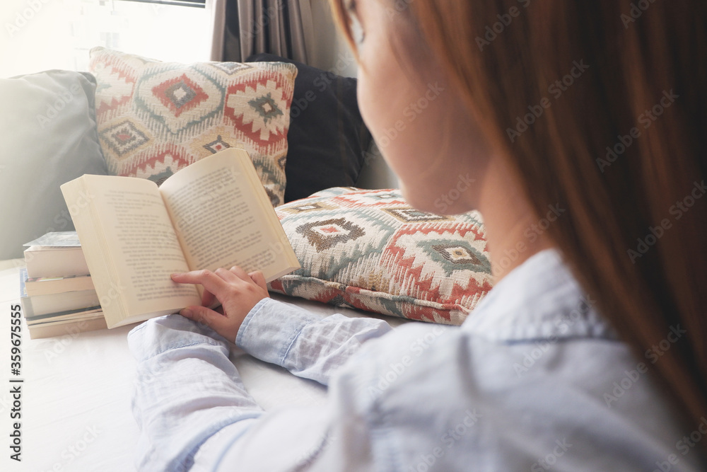 Closed up image of an asian woman reading a book comfortably. Isolating at home. Closed up image of an asian woman reading a book comfortably. Isolating at home.
