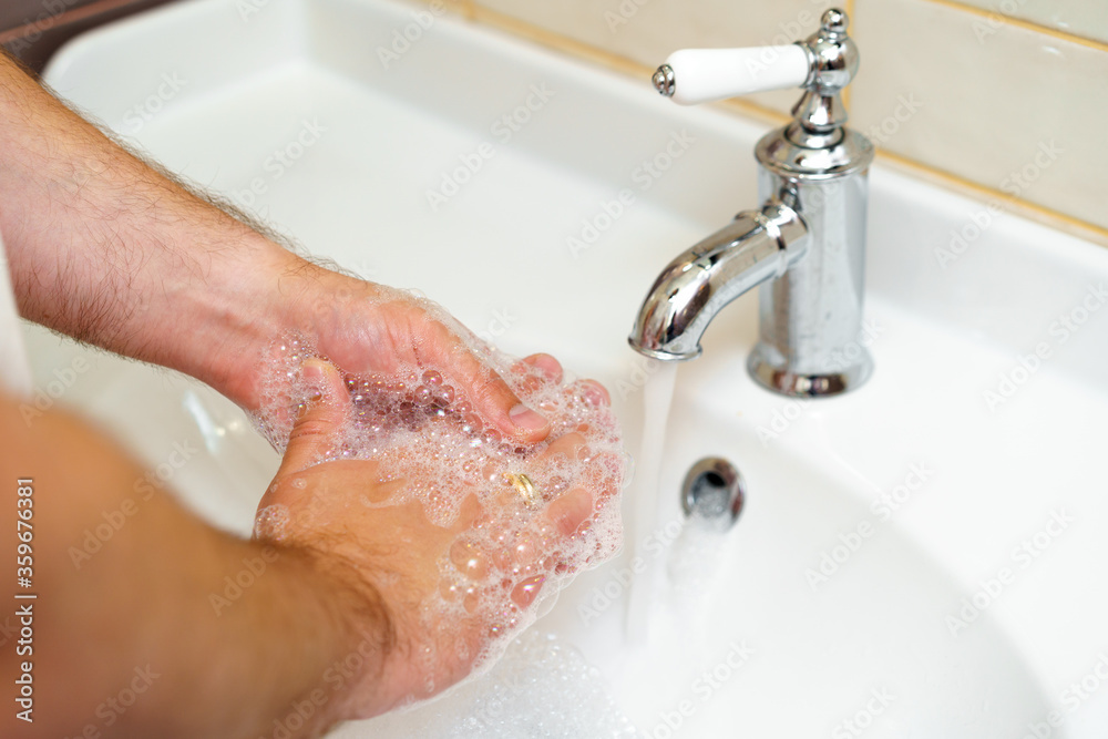 Close up photo of male hands washing with soap above the sink Close up photo of male hands washing with soap above the sink