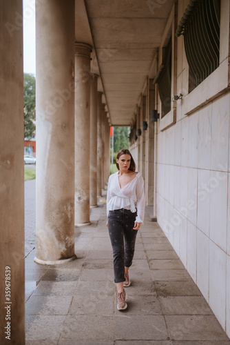A beautiful young caucasian girl in front of a white building with pillars