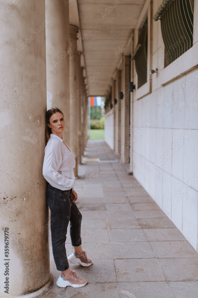 Portrait of a beautiful young caucasian girl in front of a white building