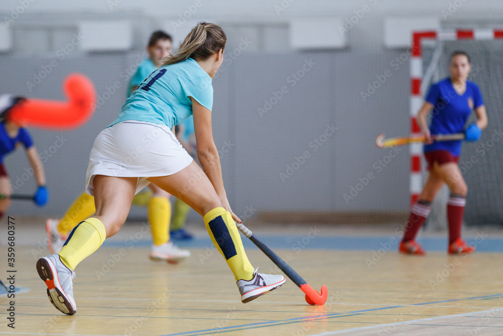 Young female indoor hockey player in attack