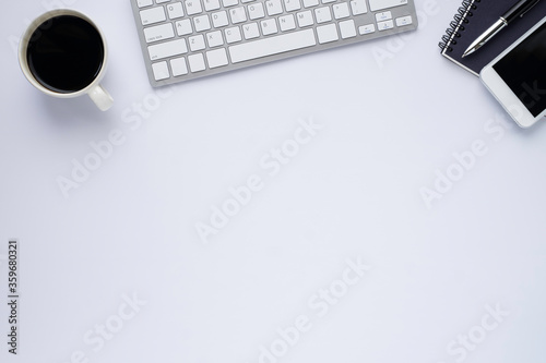 White office desk table with keyboard, notebook and coffee cup with equipment other office supplies. Business and finance concept. Flat lay with blank copy space, top view.