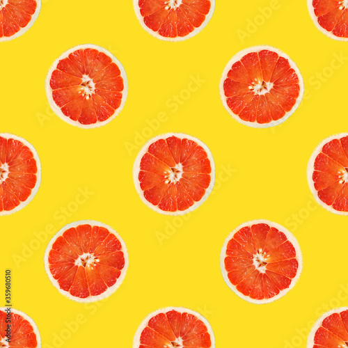 Seamless pattern from round slices of ripe juicy pink grapefruit on yellow background. Poster banner template backdrop for wallpaper product surface design tropical theme