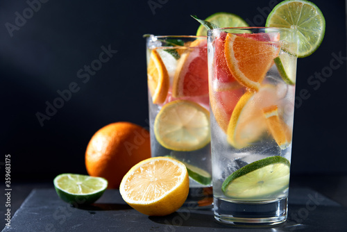 Infused water with grapefruit, orange, lemon, lime and ice on dark background