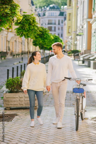 Energetic young man with bicycle and woman walking along the street