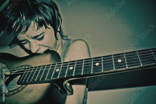 a musician girl bites the body of a guitar
