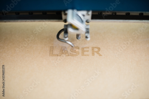 Vászonkép Industrial laser engraving word laser on cardboard, close up view