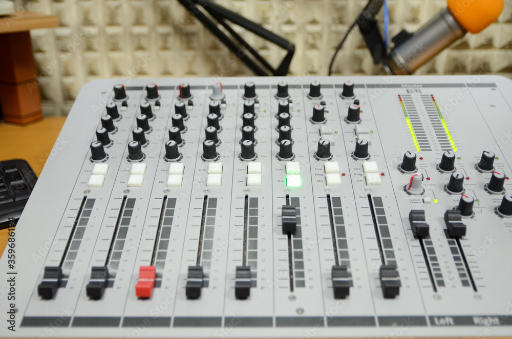 Close up of professional multitrack mixing console in production studio. Radio station. Potentiometers and VU meter lights. Equipment in studio. Recording and broadcasting program. Live show. On air.
Close up of professional multitrack mixing console in production studio. Radio station. Potentiometers and VU meter lights. Equipment in studio. Recording and broadcasting program. Live show. On air.