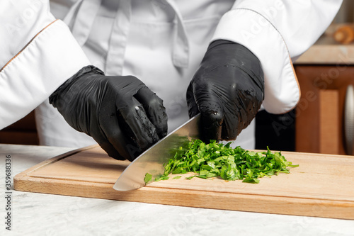 The cook cuts parsley on a wooden Board in the kitchen