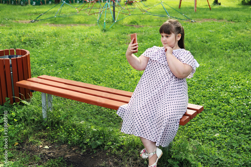 Foto Little plump girl takes selfie on smartphone
