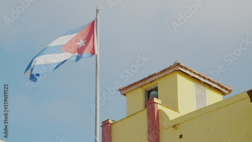 A cuban flag at the top of a yellow building in the city of Trinidad, Cuba