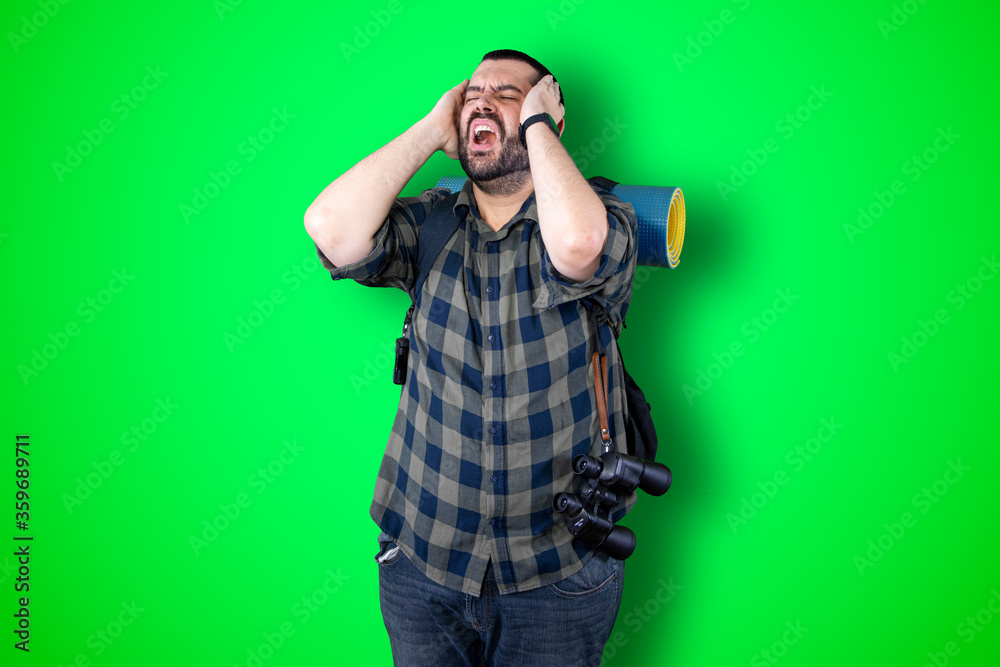 Portrait of a puzzled bearded traveler man holding hands on his head isolated over chroma background Portrait of a puzzled bearded traveler man holding hands on his head isolated over chroma background