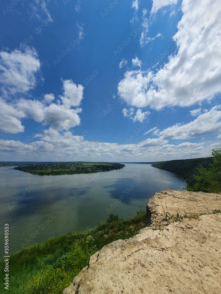 High angle, altitude view to the Nistru river, near Dubasari (Dubossary), Transnistria, Moldova. Idyllic vertical orientation scene on the peak of a cliff over the water under a rich blue sky.