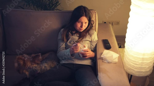 A sad girl cries and watches a melodrama on TV, next to a pet. Little dog.