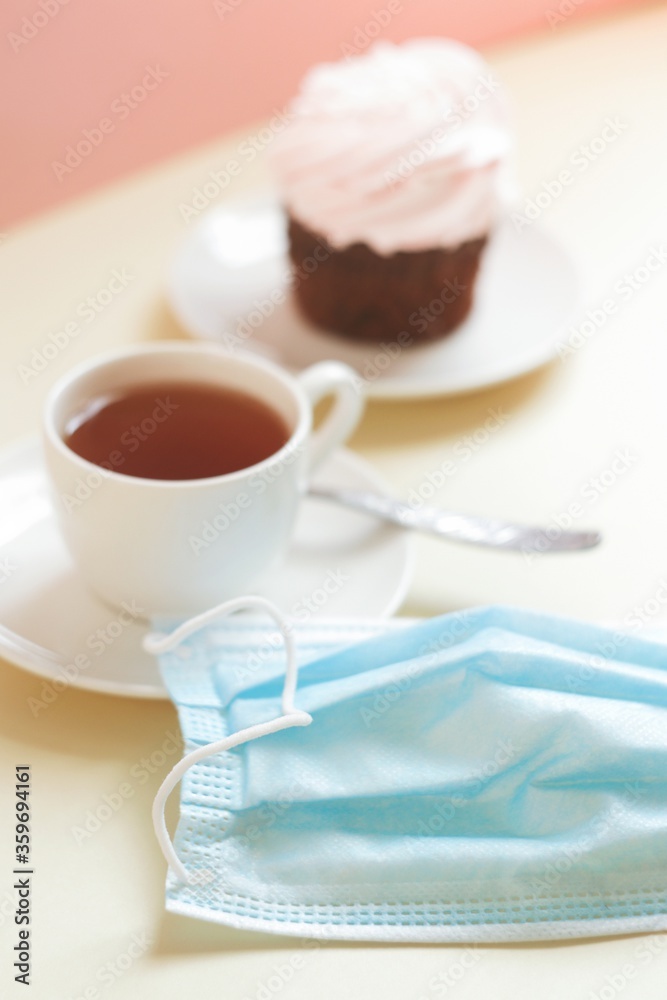 Cup of coffee and disposable face mask on a cafe table. Open restaurant, removal coronavirus COVID_19 restriction Cup of coffee and disposable face mask on a cafe table. Open restaurant, removal coronavirus COVID_19 restriction