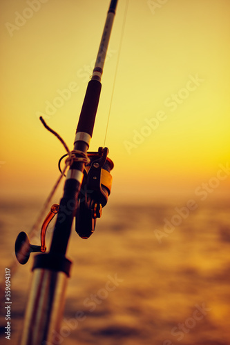 Fishing rod on a boat with sunset / sunrise and an ocean horizon.