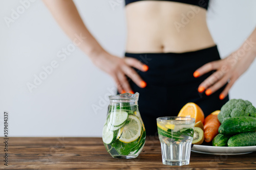 Healthy eating and dieting. Fit woman with fresh vegetables and infused water detox drink.