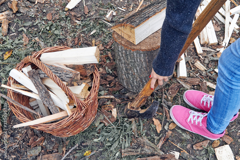 Obraz premium Woman carrying basket with cut woods prepared for winter.