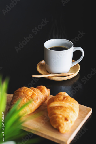 Two fresh croissants and cup of coffee on dark stone table