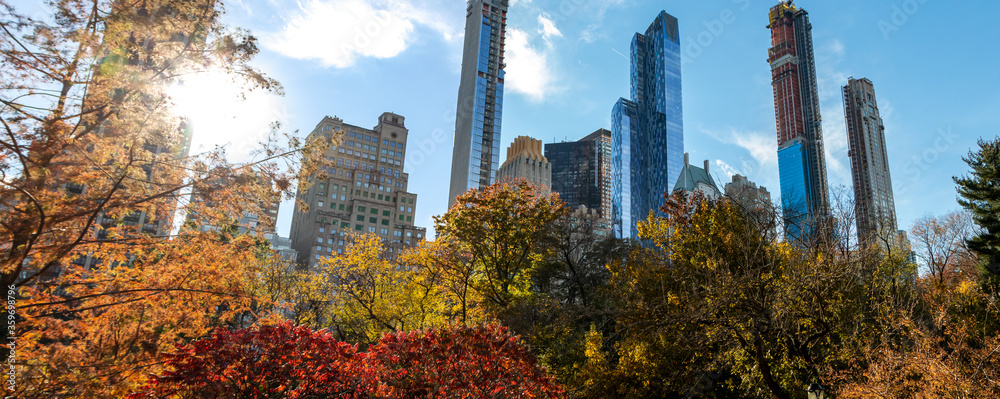 Sunset behind the New York City skyline with the buildings of Manhattan framed by colorful fall trees of Central Park
