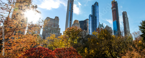 Obraz na płótnie Sunset behind the New York City skyline with the buildings of Manhattan framed by colorful fall trees of Central Park w salonie