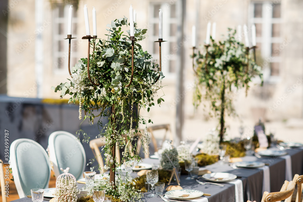 wedding table decorated by plates, knives and forks, candle, moss and greenery