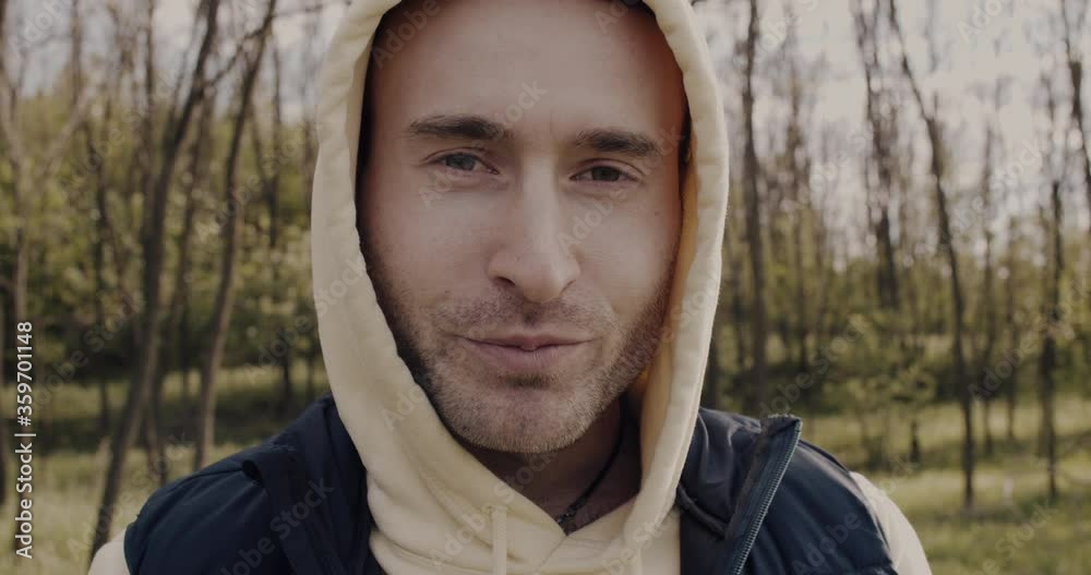 a smiling and well-disposed man with a hood on his head, looks into the room and eats a sweet dessert. a smiling and well-disposed man with a hood on his head, looks into the room and eats a sweet dessert.