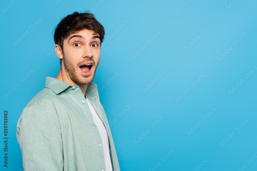 shocked young man with open mouth looking at camera isolated on blue shocked young man with open mouth looking at camera isolated on blue
