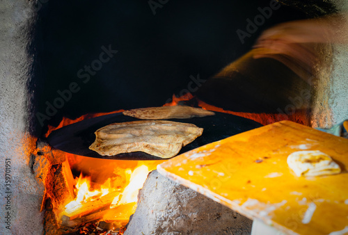 Hand making gozleme bread on wooden fire with motion blur in rural  region in Turkey photo