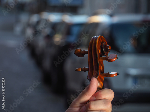 Male adult violinist hand holding antiquized handmade cremonese violin in the street at dawn in city street waiting to re start and play again in concert after coronavirus outbreaak photo