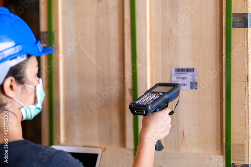Closeup hand hold bar code scanner at wood box in warehouse