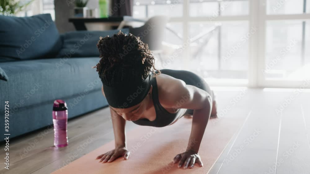 Black athletic young woman performing push-up exercises on mat practicing warm-up training bodybuilding at home. Keeping in shape. Fitness. Sports routine.
