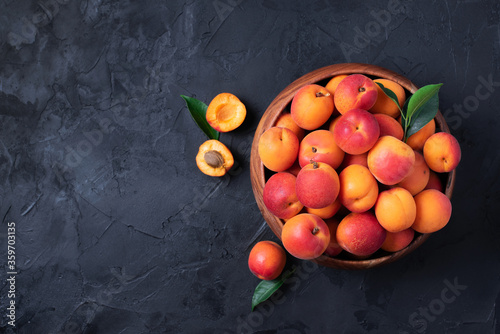 Ripe apricots on black background. Top view, copy space. Fruit banner. Healthy vegetarian food, detox or diet concept. Fruit summer concept. Bowl of harvested apricots for jam