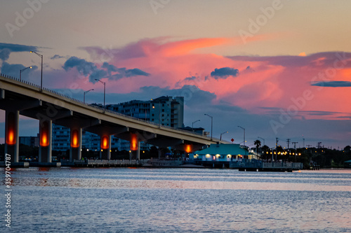 Bridge Over River With Buildings and Colorful Clouds in Background photo