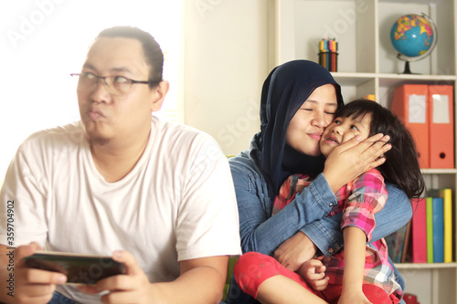 Fotografi Asian father jealous of his own child, mom takes care of her daughter makes dad